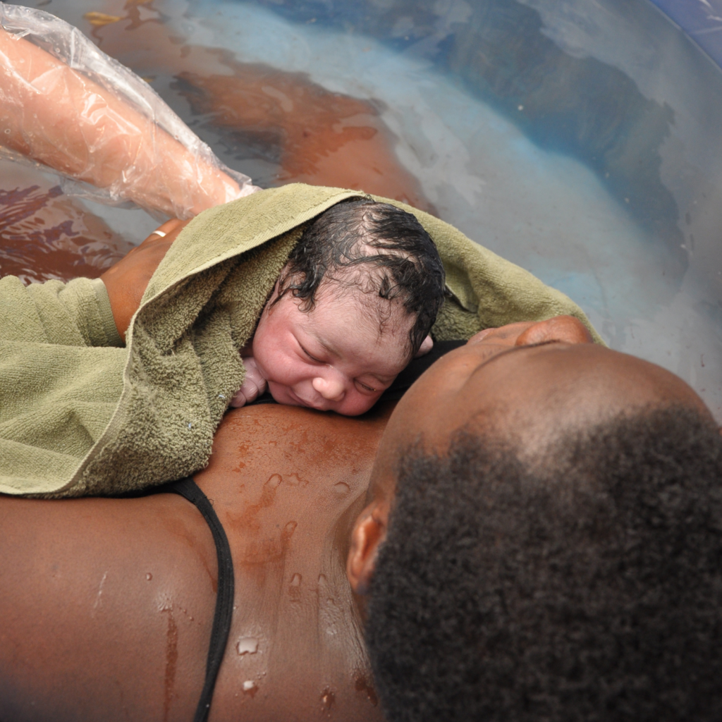 Black morther holding new born baby after having a water birth at home