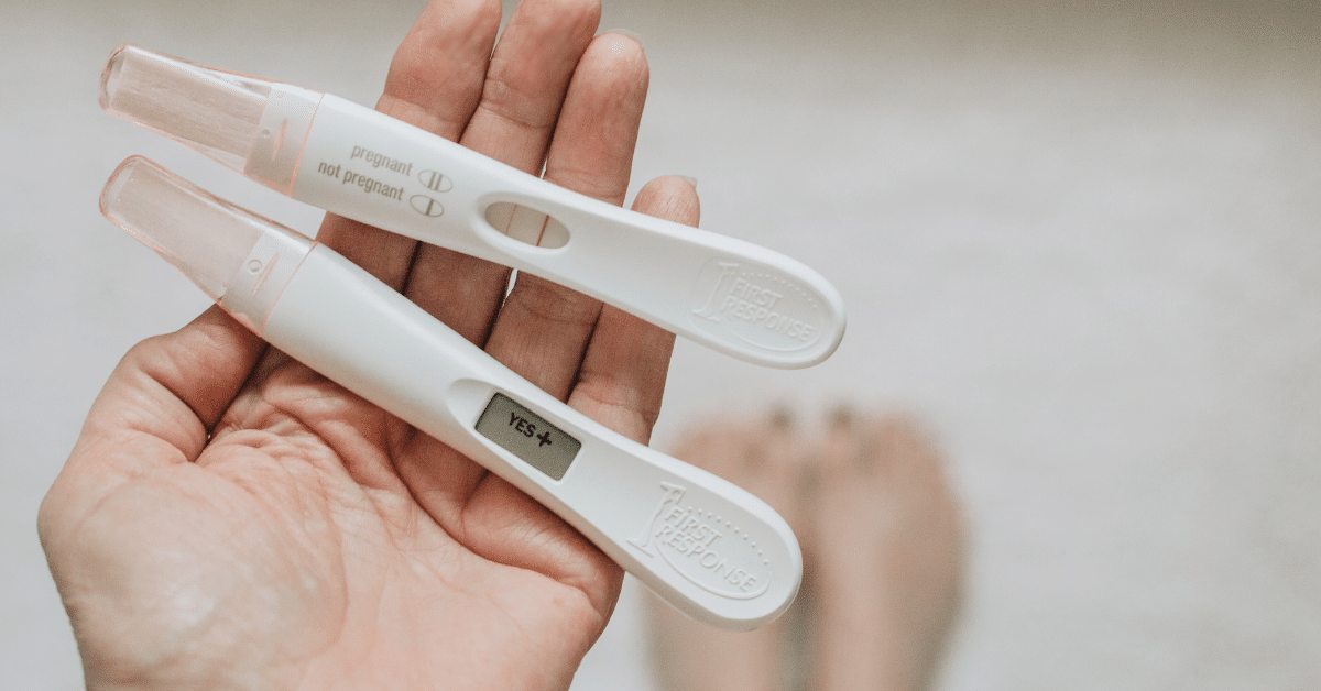 Woman holding two positive pregnancy tests in her open hand now in the first month of pregnancy