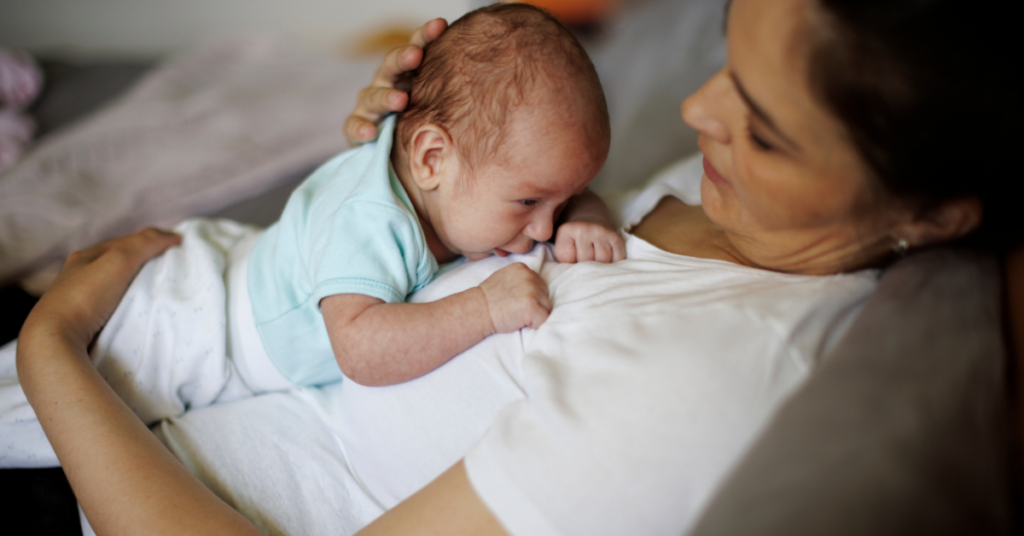 A mom in a white tshirt holding her baby on her chest two months postpartum