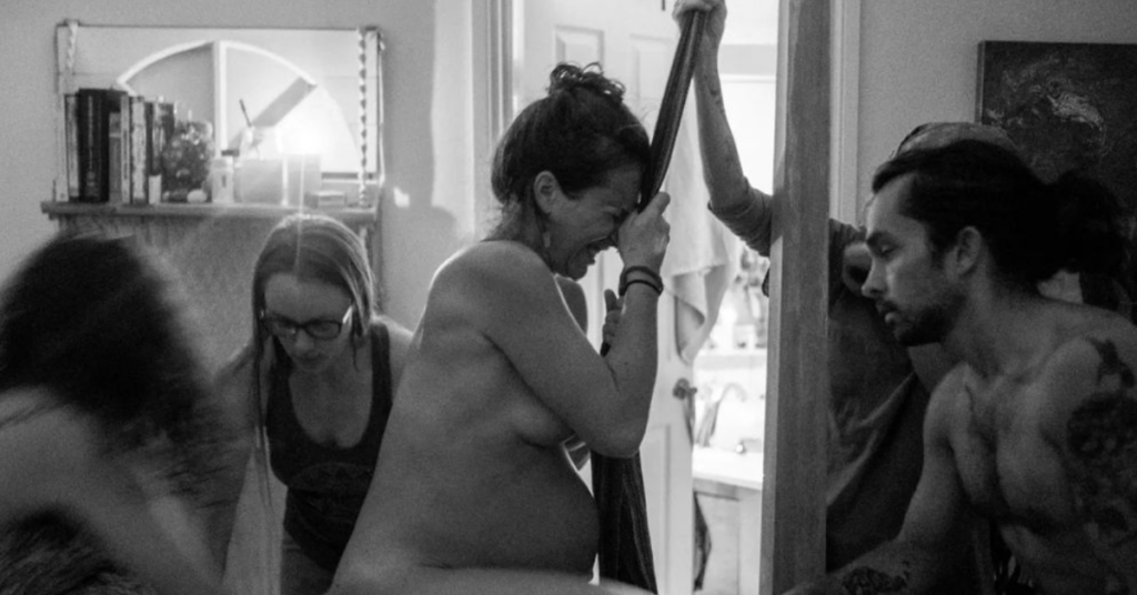 A woman giving birth at home standing up.