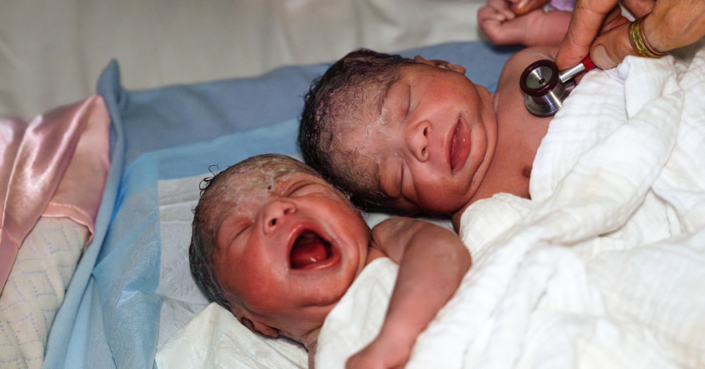 two babies after twin birth being monitored by midwife with stethoscope