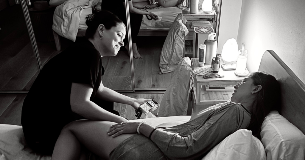 Midwife providing prenatal care for woman laying in bed